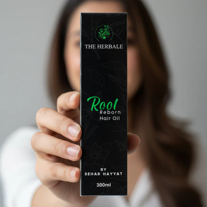 Hand holding The Herbale Root Reborn Hair Oil 300ml box, highlighting the product packaging.
